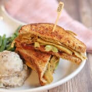 Vegan Thanksgiving leftovers sandwich on plate with green beans and mashed potatoes.