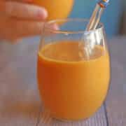 Sweet potato smoothie in glass with straw.