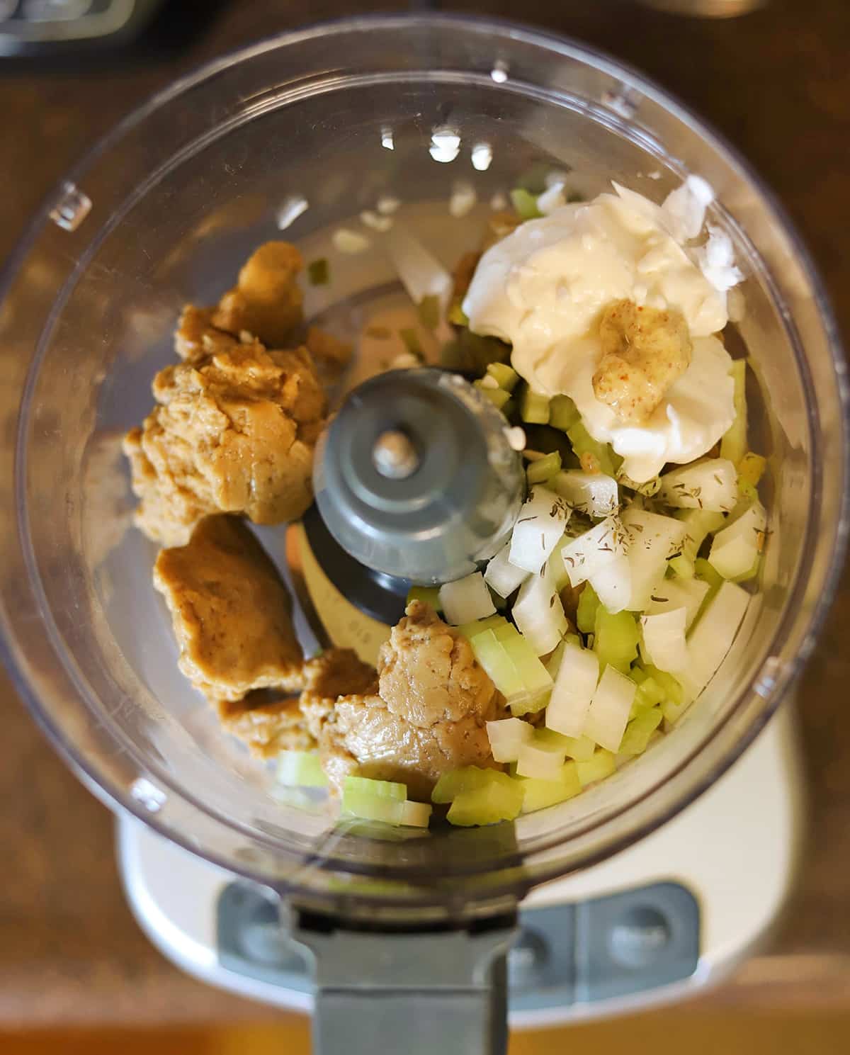 Seitan, celery, onions, spices, vegan mayo, and mustard in food processor.