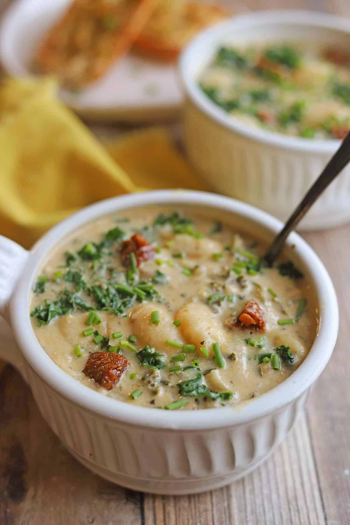 Gnocchi swimming in bowl of soup with cashew cream, kale, and browned vegan sausage.