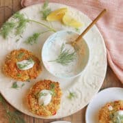 Vegan lemon dill sauce with capers in bowl by artichoke crab cakes.