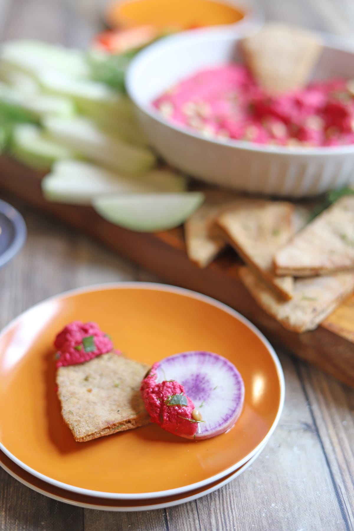 Daikon radish and toasted pita chip on plate with air fryer beet hummus.