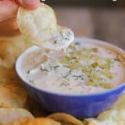 Text overlay: vegan dill pickle dip, cadryskitchen.com. Potato chip dunked in creamy dill pickle dip.