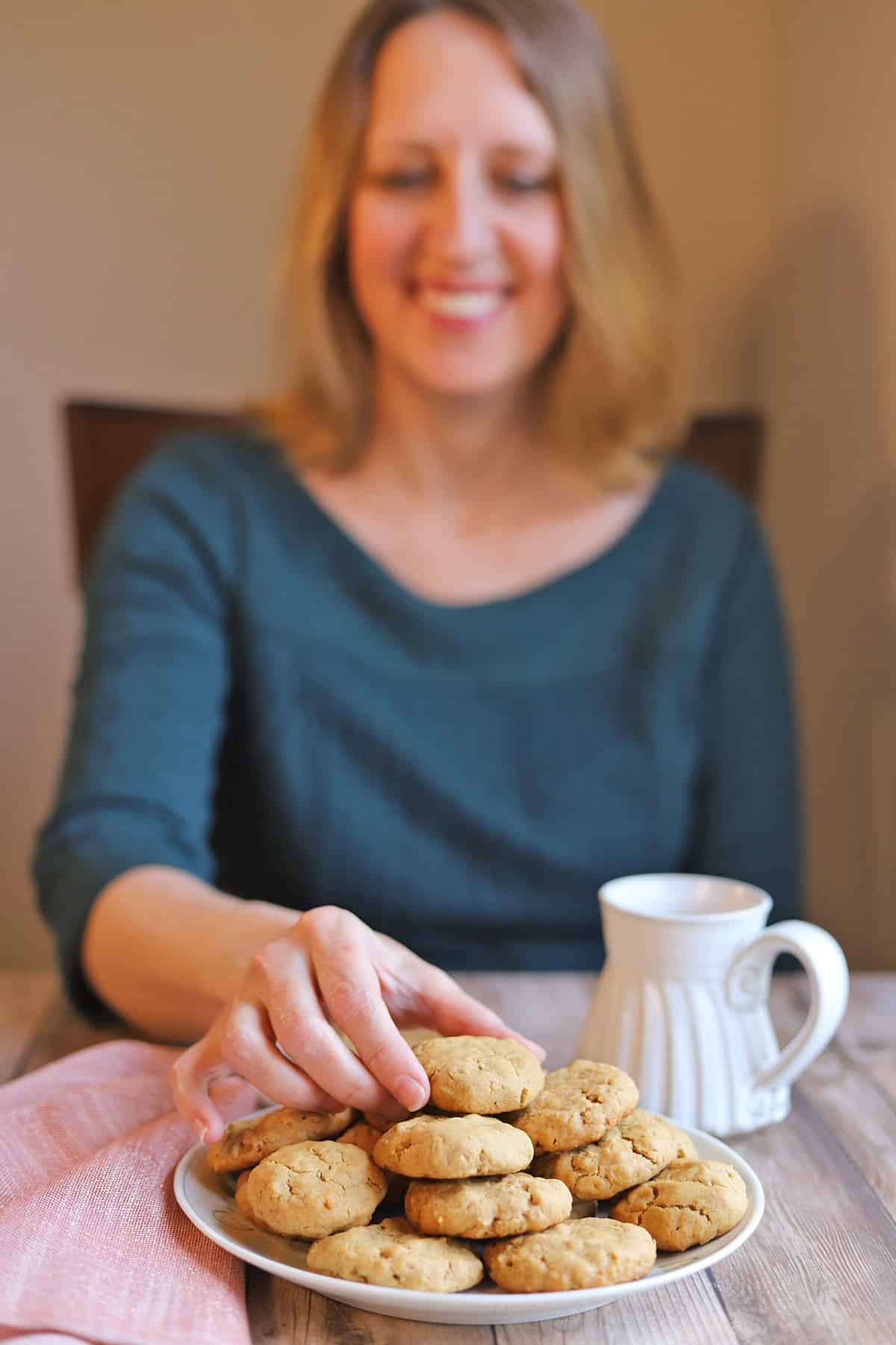 Cadry smiling at platter of vegan oatmeal and peanut butter cookies.