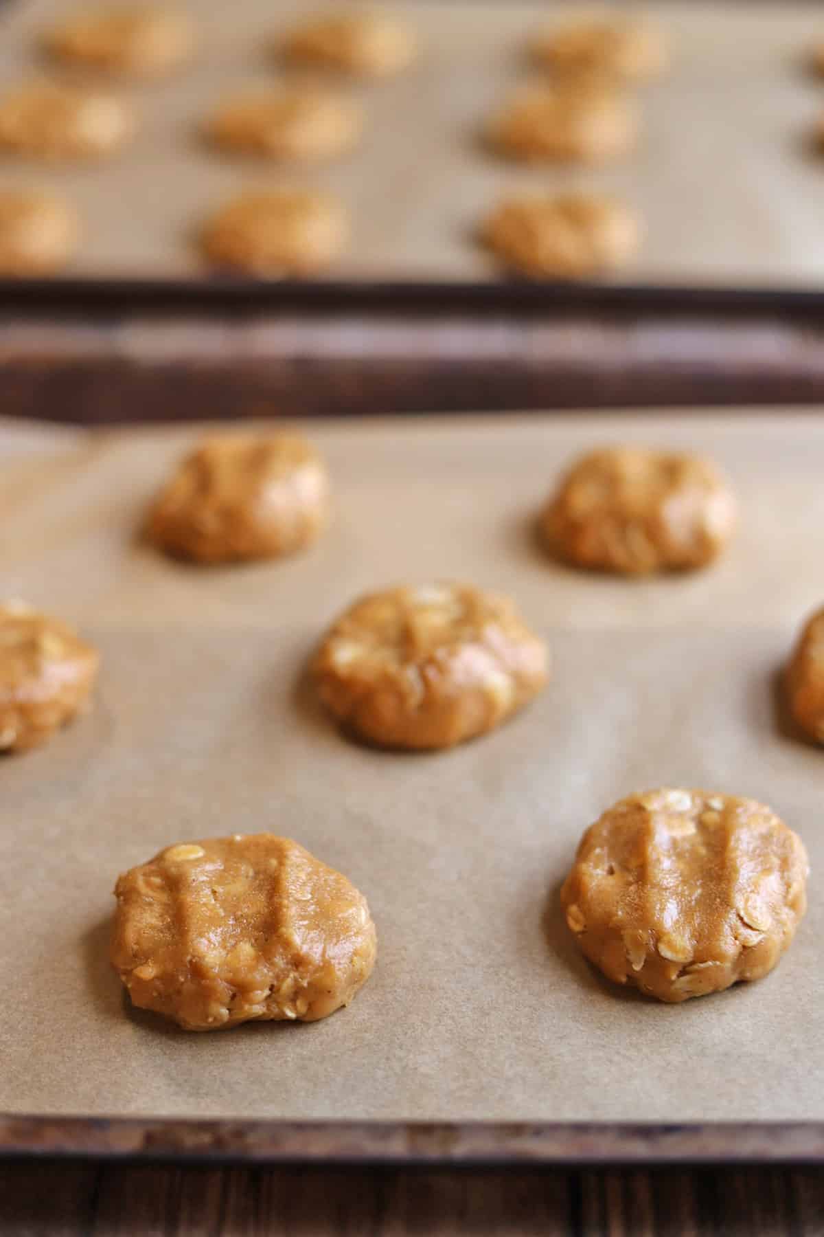 Cookie dough dollops on baking sheets with parchment paper.