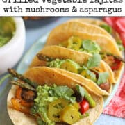 Text overlay: cadryskitchen.com, grilled vegetable fajitas with mushrooms & asparagus. Fajitas on platter with mushrooms, asparagus, and bell pepper topped with guacamole and jalapenos.