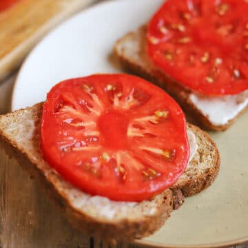 Slices of toast with vegan mayo, thickly cut tomatoes, and sprinkling of salt.
