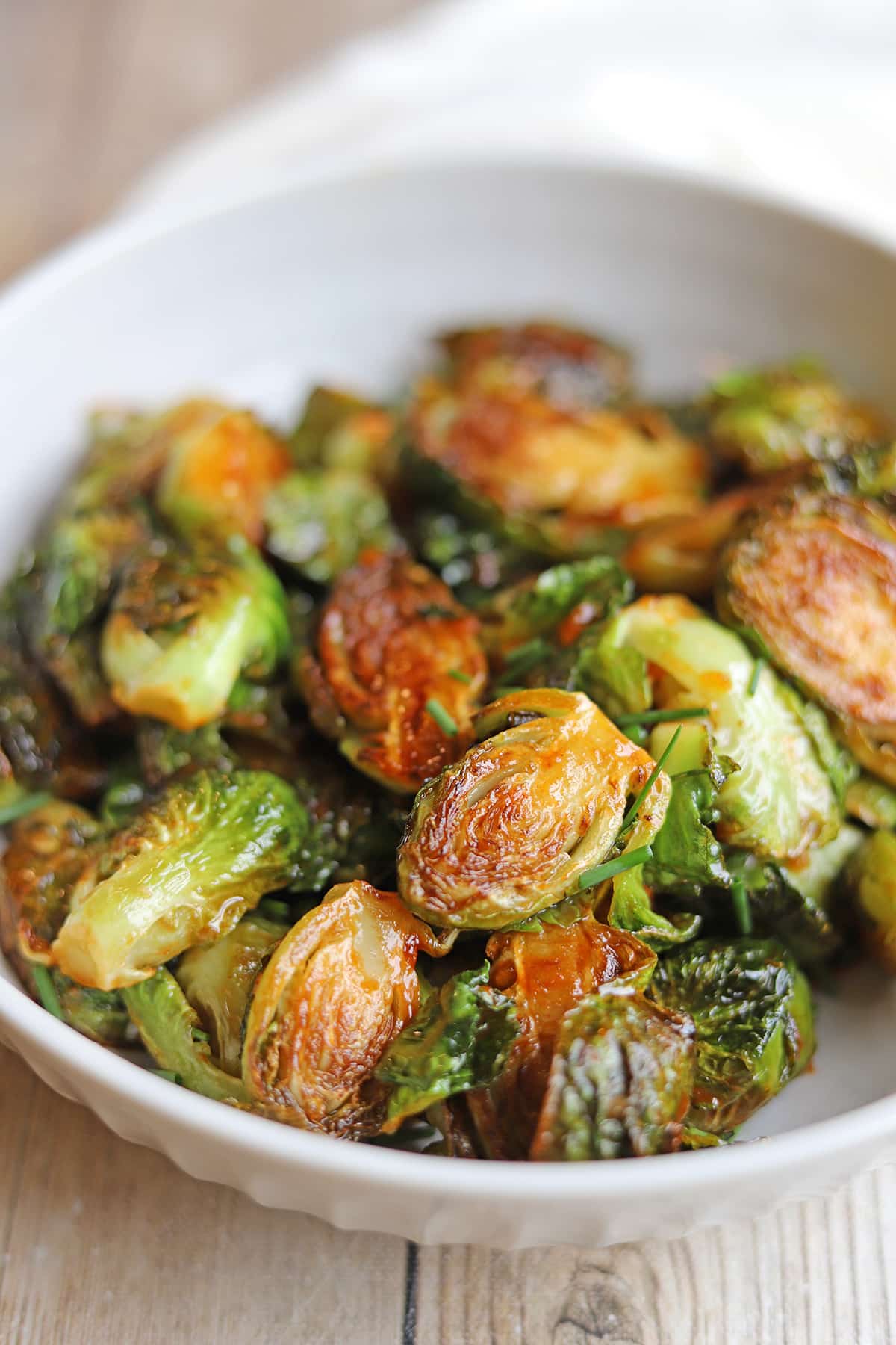 Pan-fried Brussels sprouts side dish with gochujang glaze in white bowl.