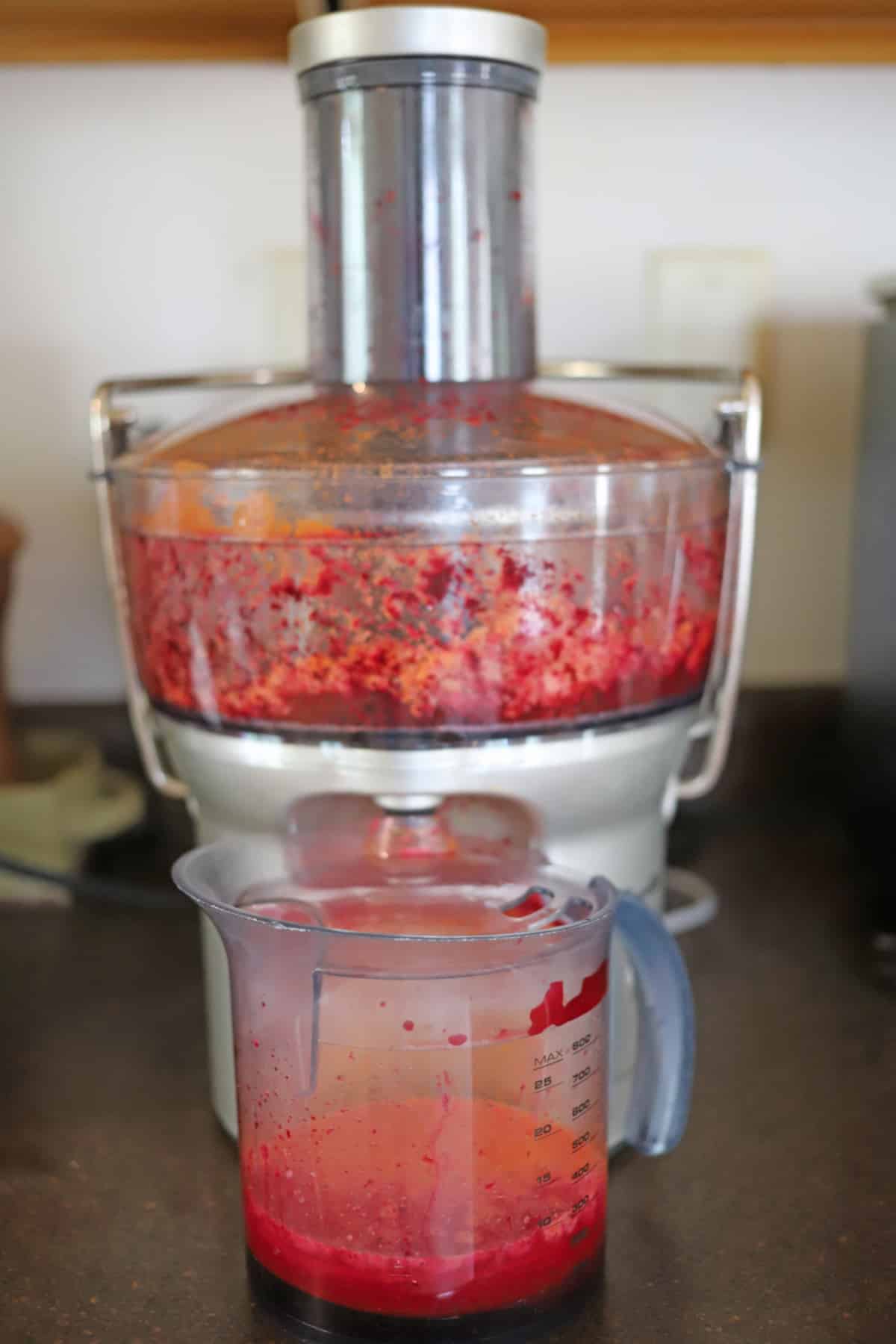 Juicer with pitcher of beet, carrot, apple juice.