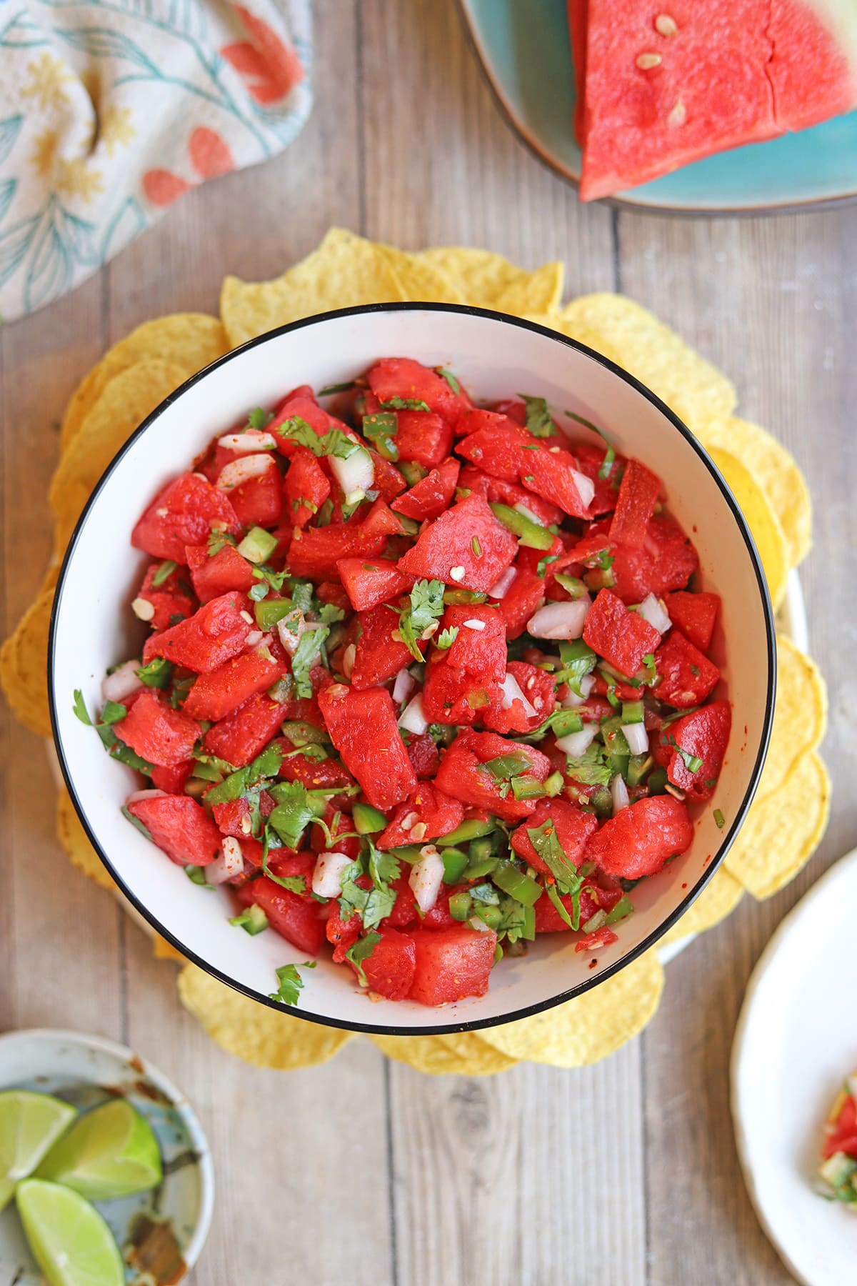 Watermelon salsa in bowl by limes.