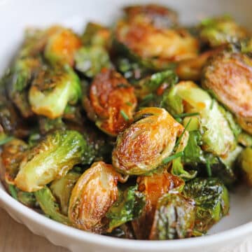 Pan fried Brussels sprouts glistening with gochujang garlic glaze in bowl.