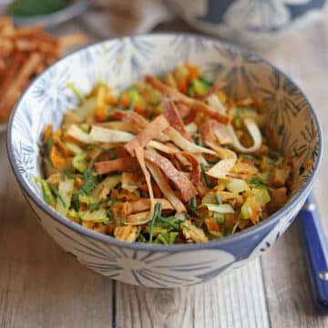 Stir-fried napa cabbage, carrots, and onions in bowl with crispy air fried wonton wraps.