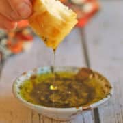 Dipping oil streaming off a piece of bread and into oil dish.