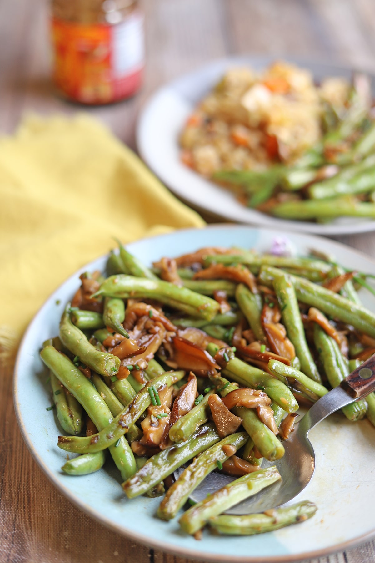 Asian style green beans with shiitake mushrooms on plate with spoon.
