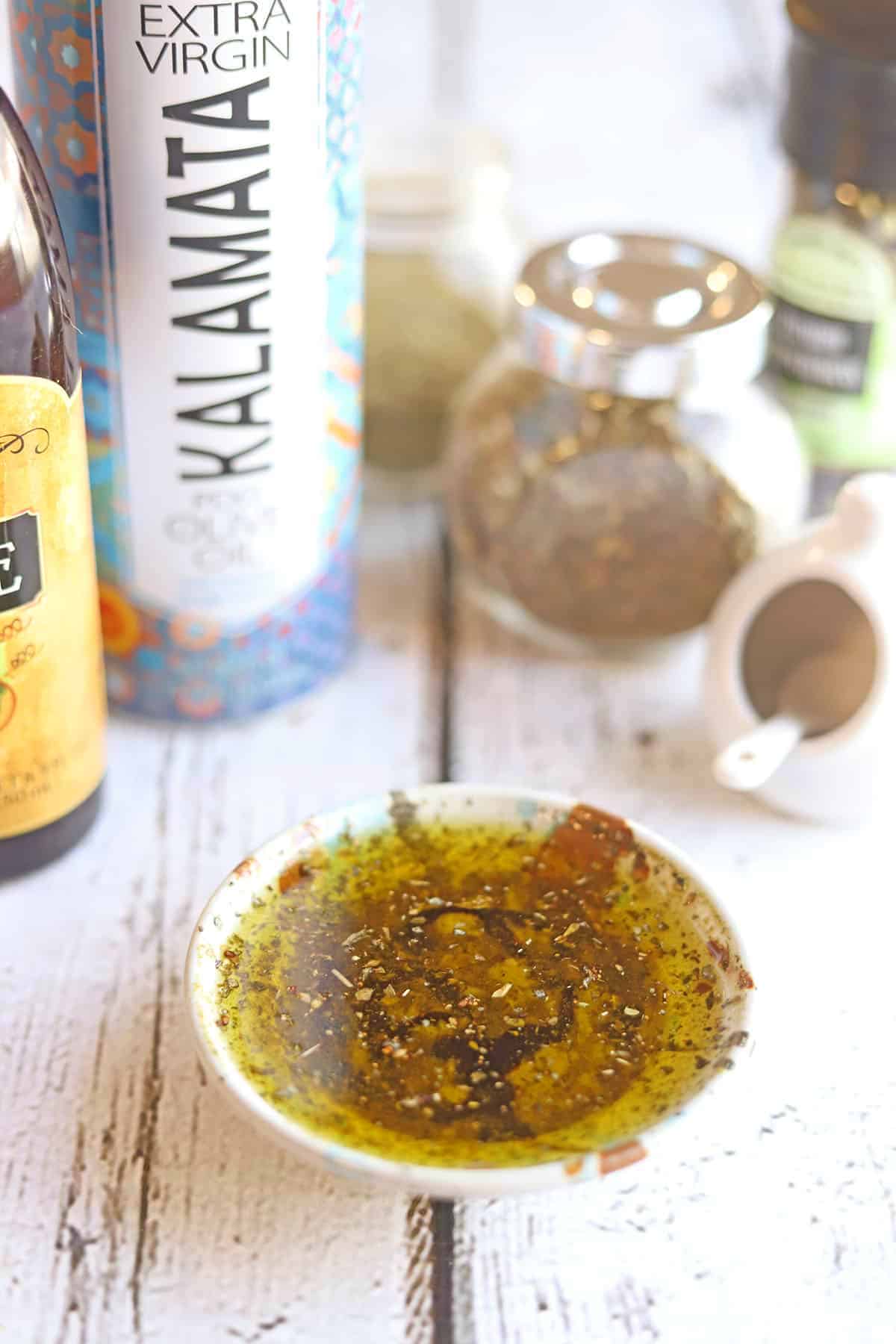 Bowl of bread dip oil surrounded by ingredients.