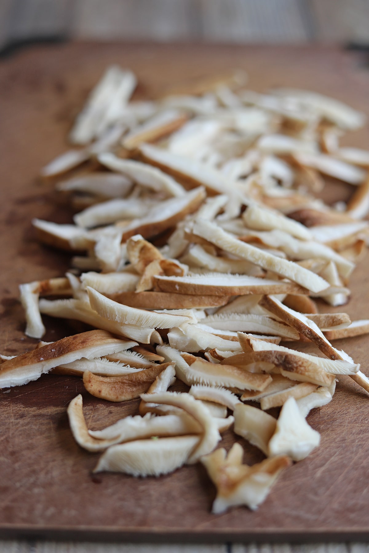 Thin slices of shiitake mushrooms on cutting board.