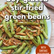 Text overlay: Soy-glazed stir-fried green beans with shiitake mushrooms. Get the recipe at cadryskitchen.com. Platter of stir-fried green beans and mushrooms.