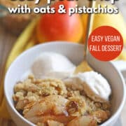 Text overlay: Cozy pear crisp with oats & pistachios. Easy vegan fall dessert. Get the recipe at cadryskitchen.com. Bowl of cinnamon dusted pear crisp with dollops of melty non-dairy ice cream.