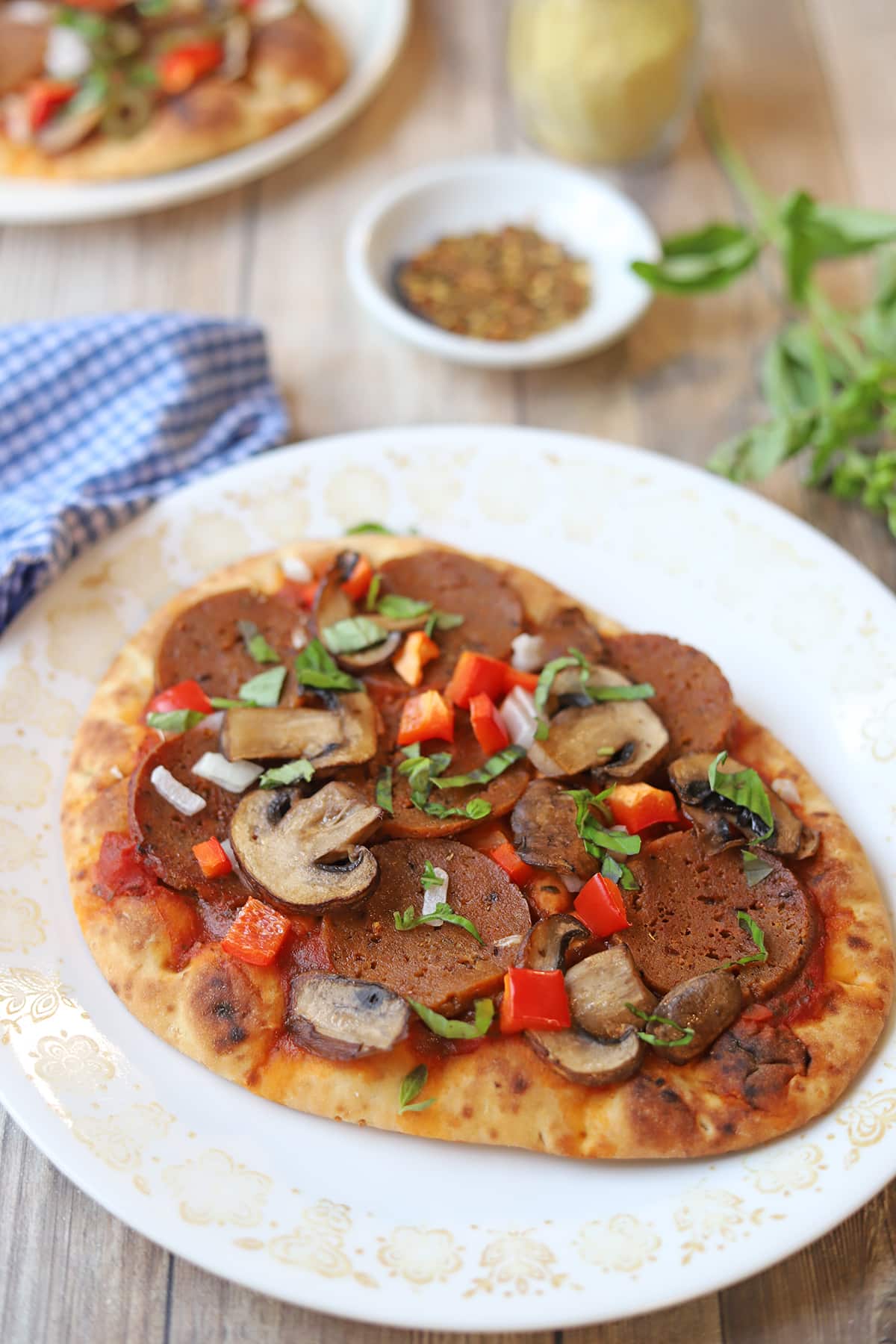 Flatbread pizza with vegan pepperoni, mushrooms, onion, bell pepper, and fresh basil.