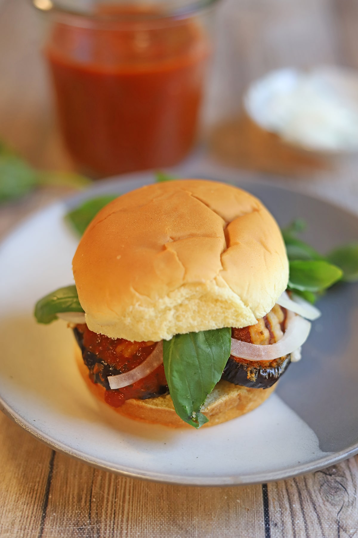 Vegan eggplant parmesan sandwich on plate by marinara.