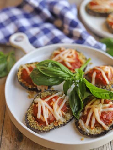 Vegan breaded eggplant on plate with marinara and non-dairy cheese.