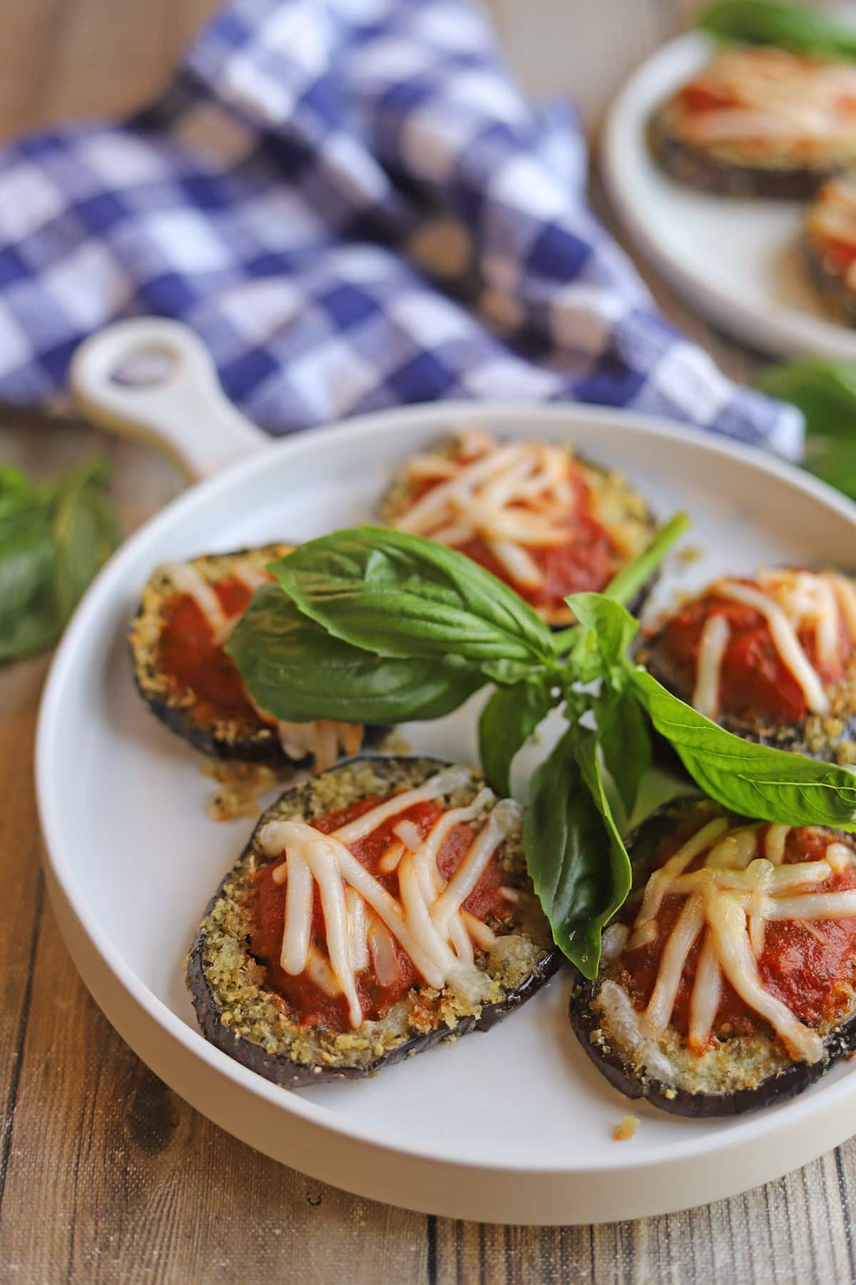 Vegan breaded eggplant on plate with marinara and non-dairy cheese.