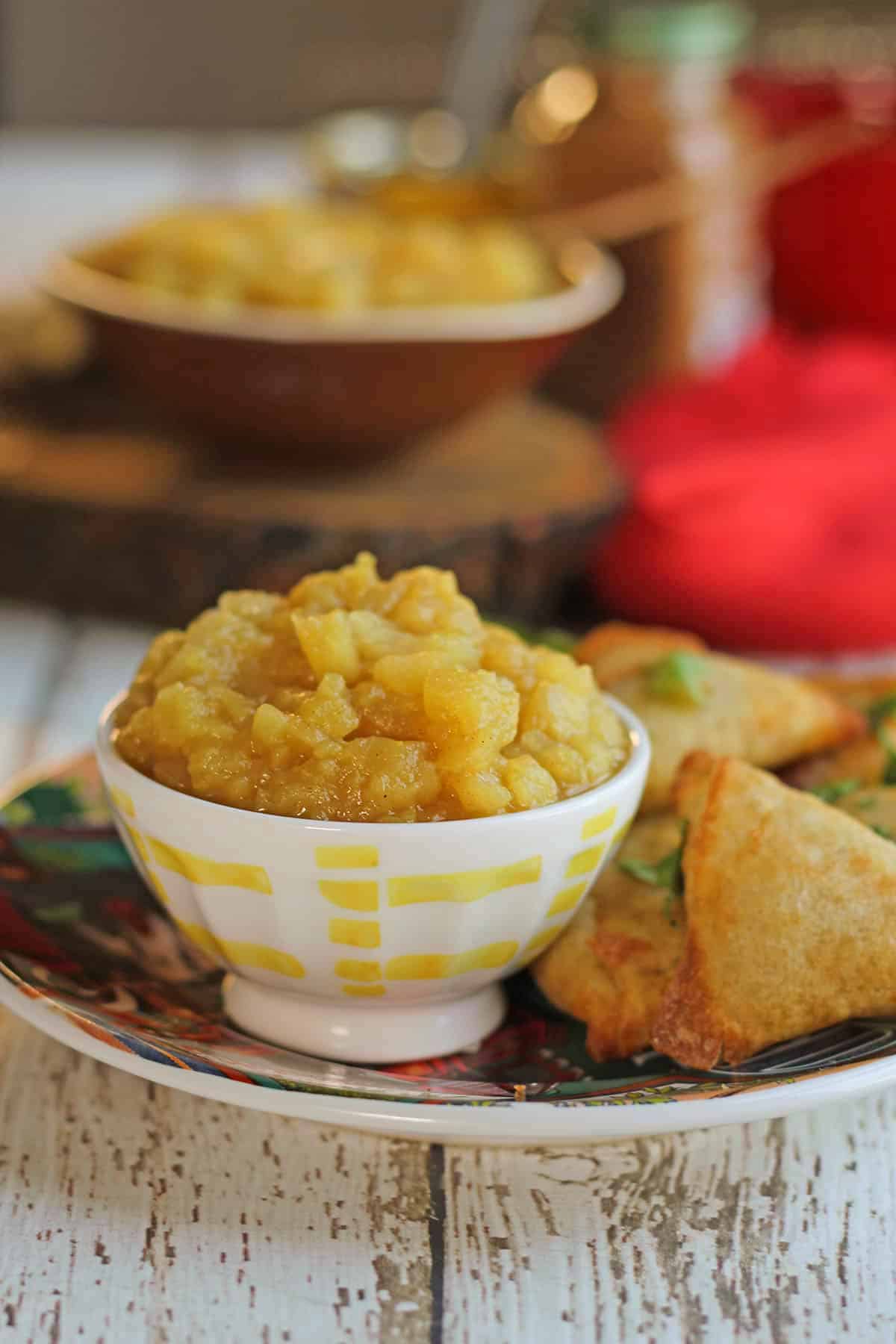Apple chutney in small serving bowl by vegetable samosas.