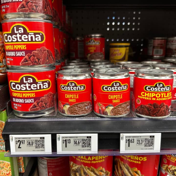 Cans of chipotle peppers in adobo sauce and chipotle sauce on store shelf.