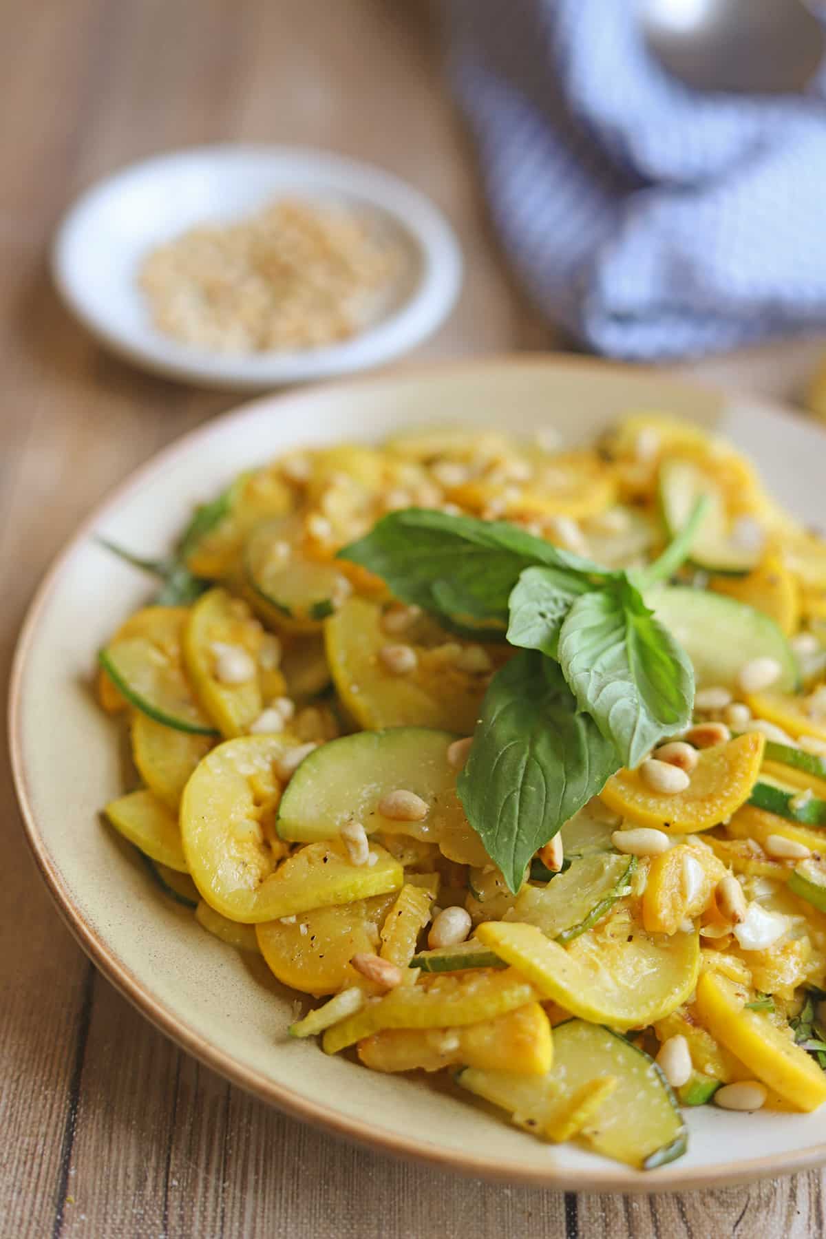 Garlicky zephyr squash and zucchini on plate garnished with fresh basil.