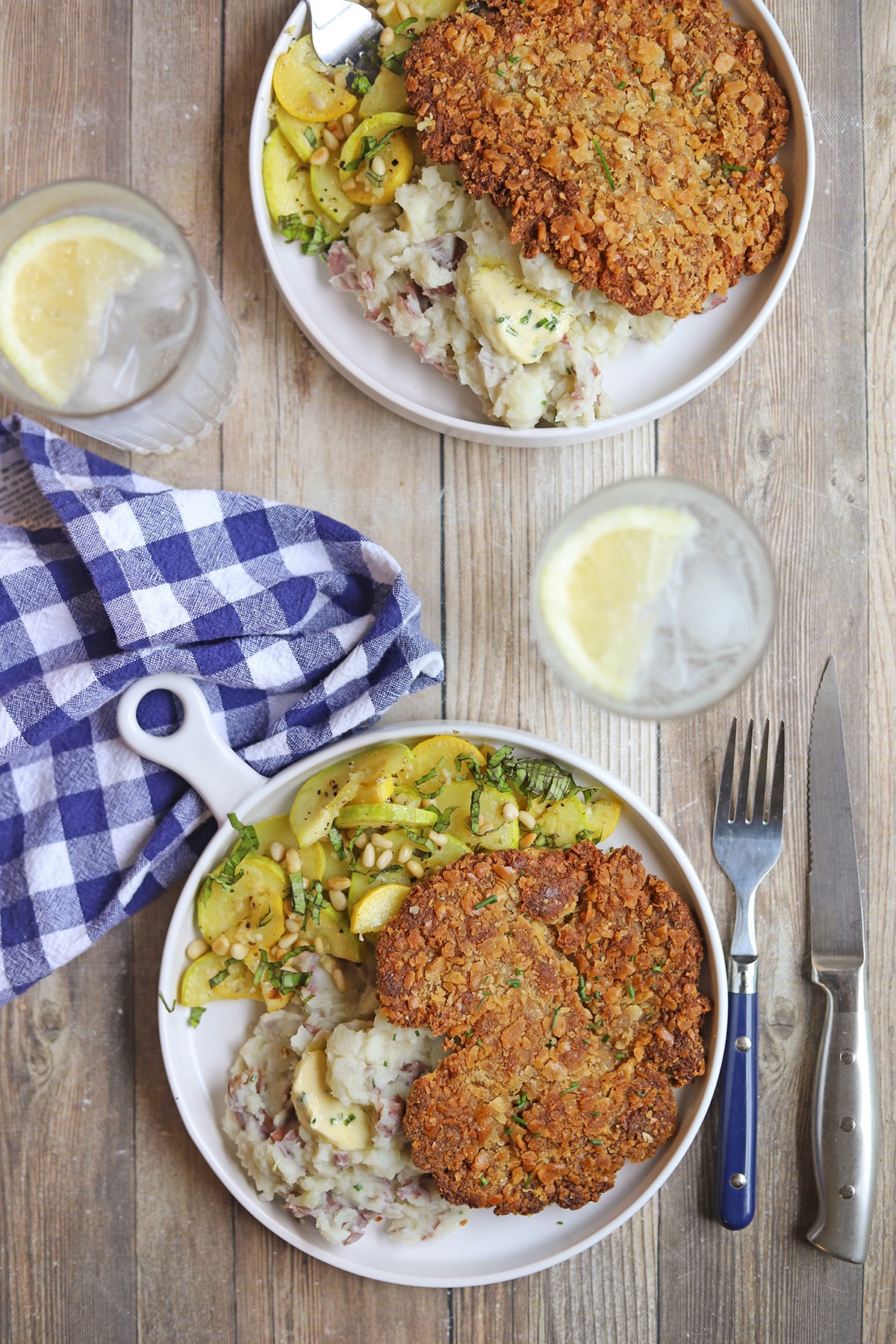 Dinner plates of breaded vegan cutlets with summer squash and mashed potatoes.