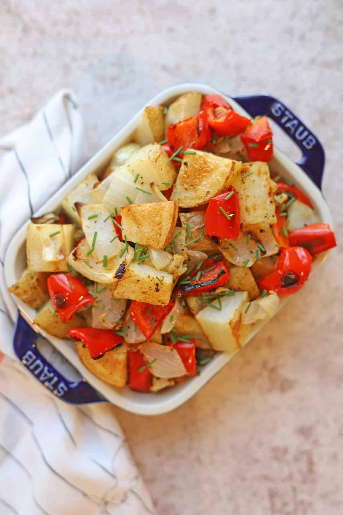 Oven roasted potatoes, red bell pepper, and onions in serving dish.