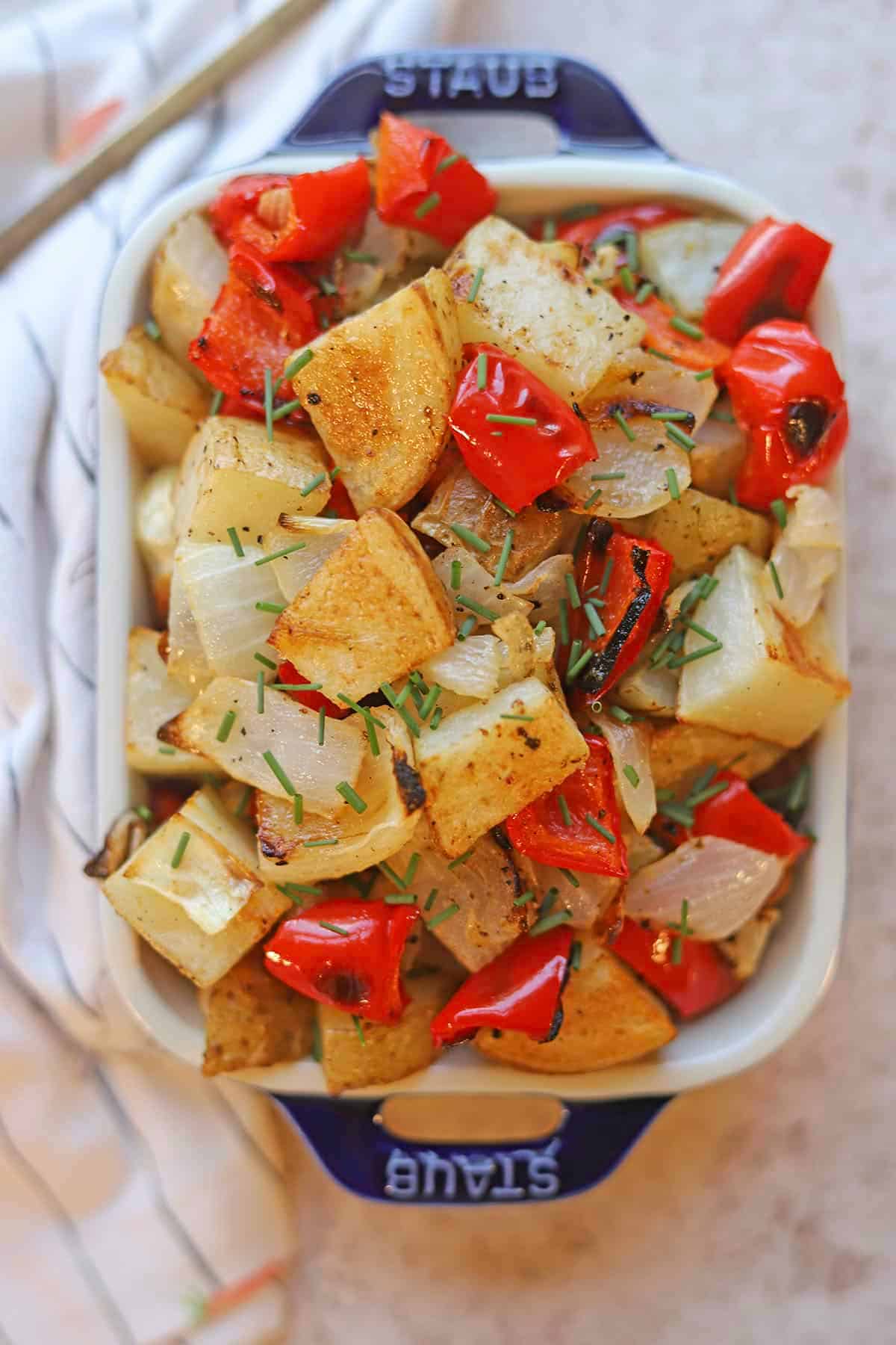 Roasted potatoes, onions, and bell peppers in serving dish.