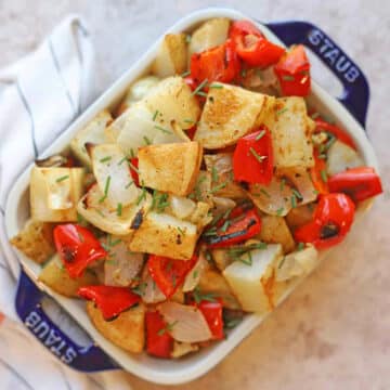 Oven roasted potatoes with peppers and onions in casserole dish.