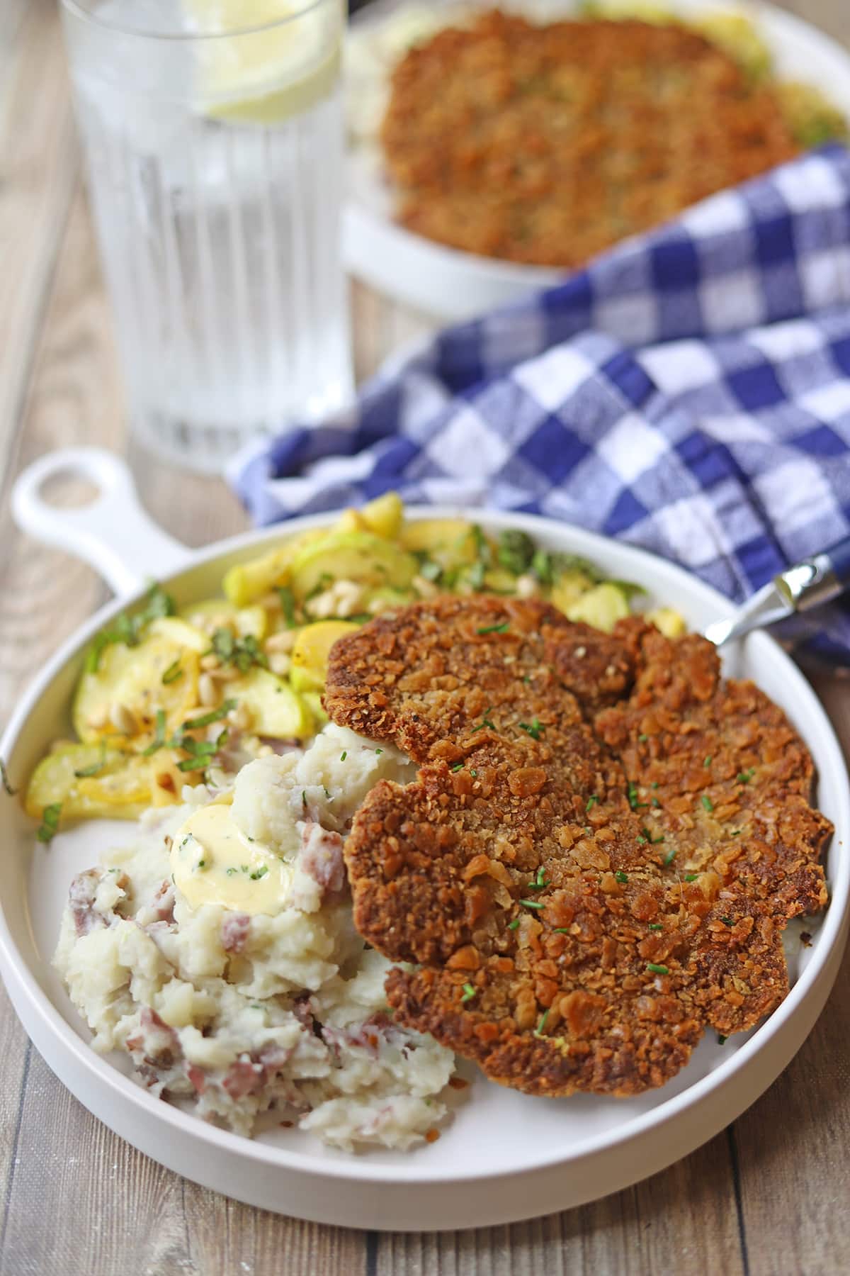 Vegan pork schnitzel on plate with mashed potatoes and squash side dish.