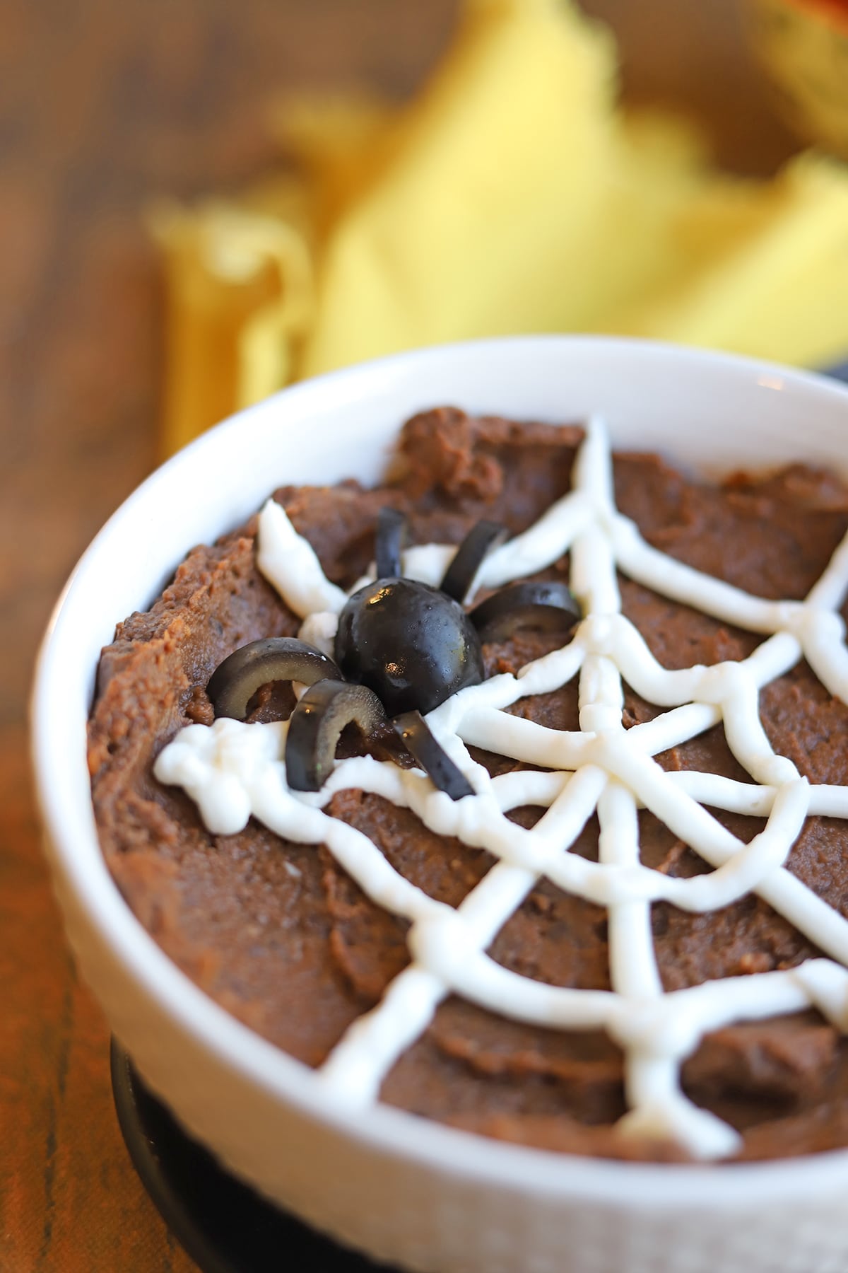Black olive spider sitting on non-dairy sour cream web and chipotle black bean dip.