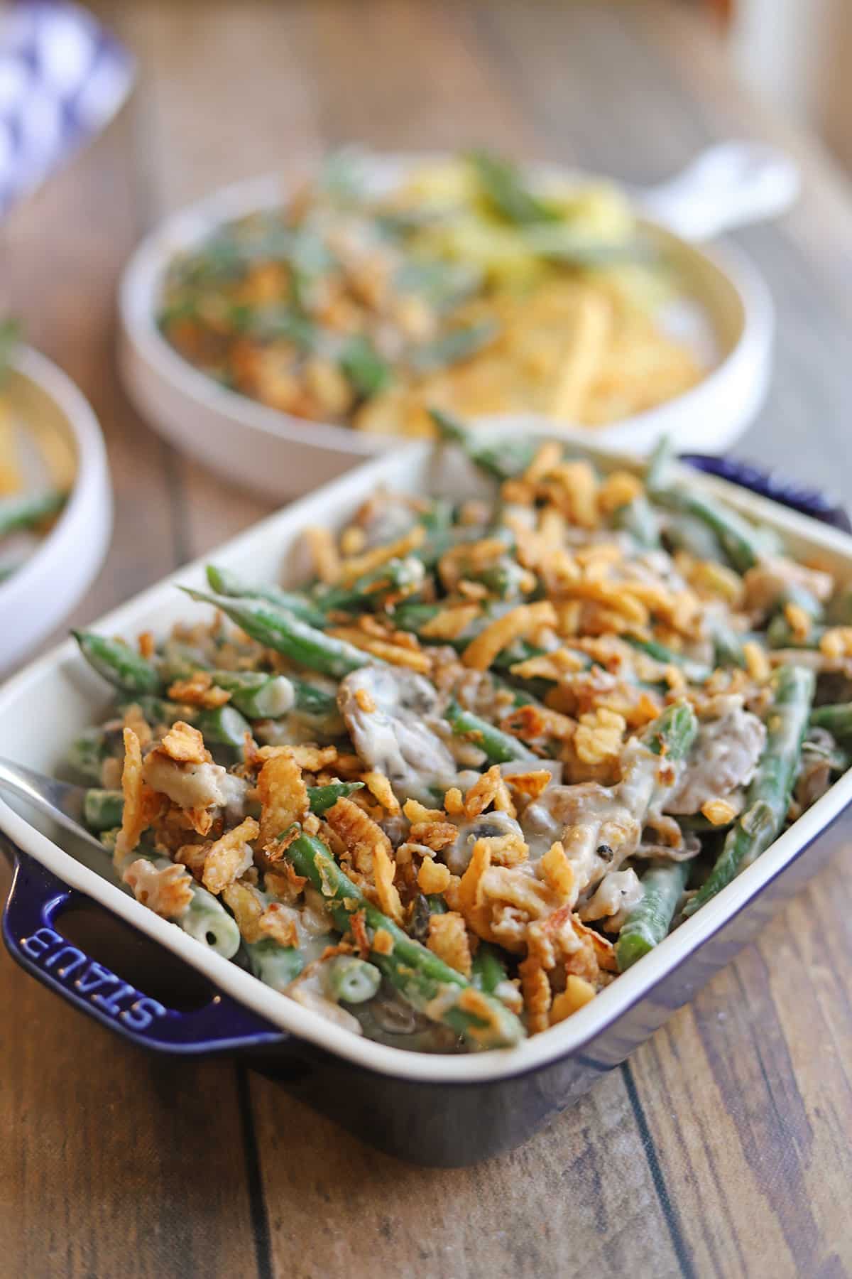 Vegan green bean casserole in serving dish, topped with fried onions.
