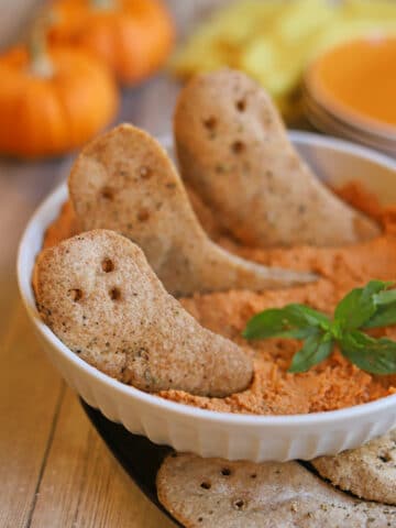 Air fried pita ghost chips in bowl of hummus.