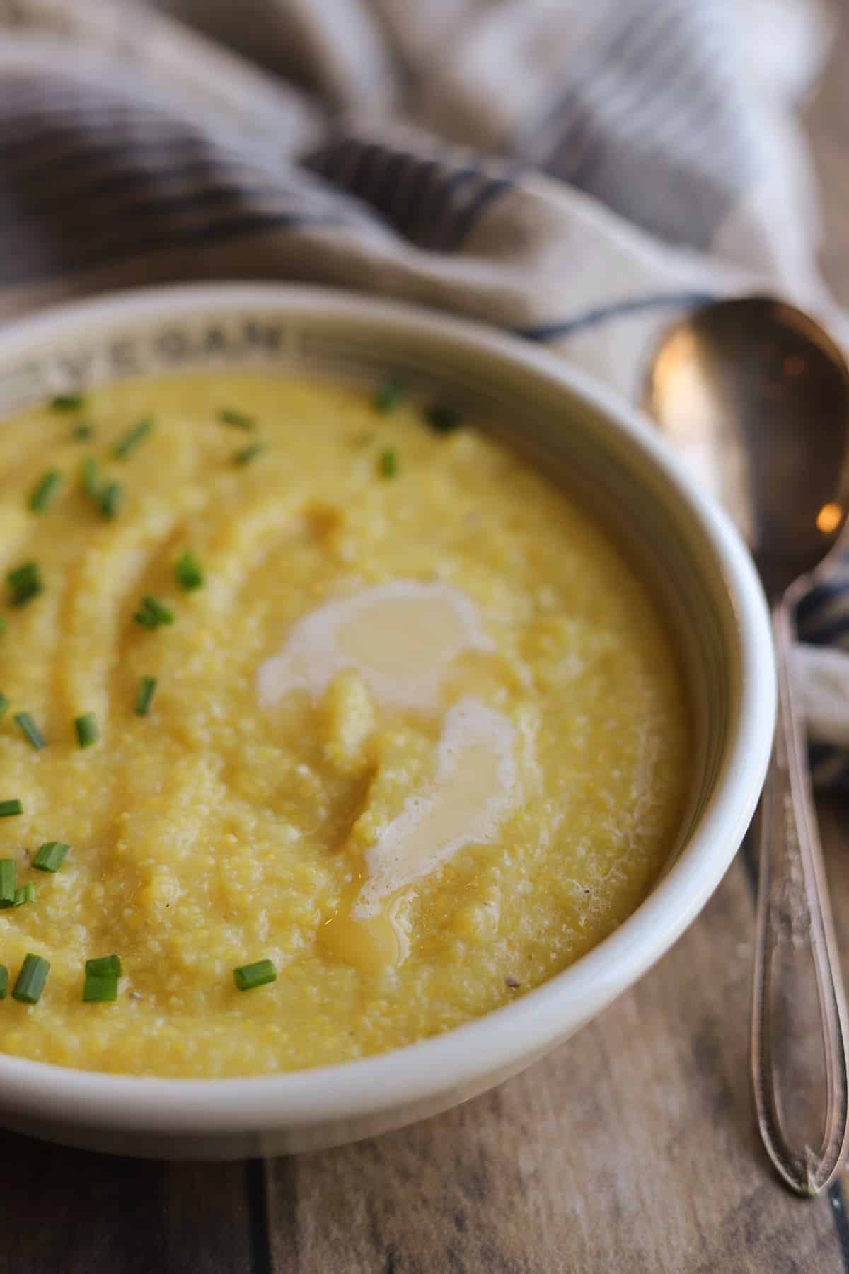 Creamy Southern-style vegan grits in bowl with melted non-dairy butter and chives.