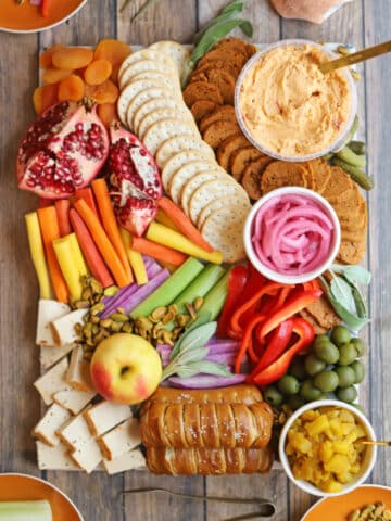 Thanksgiving charcuterie board with vegan pimento cheese, vegan mustard cheese, apple chutney, olives, carrots, dried apricots, and vegan pepperoni.