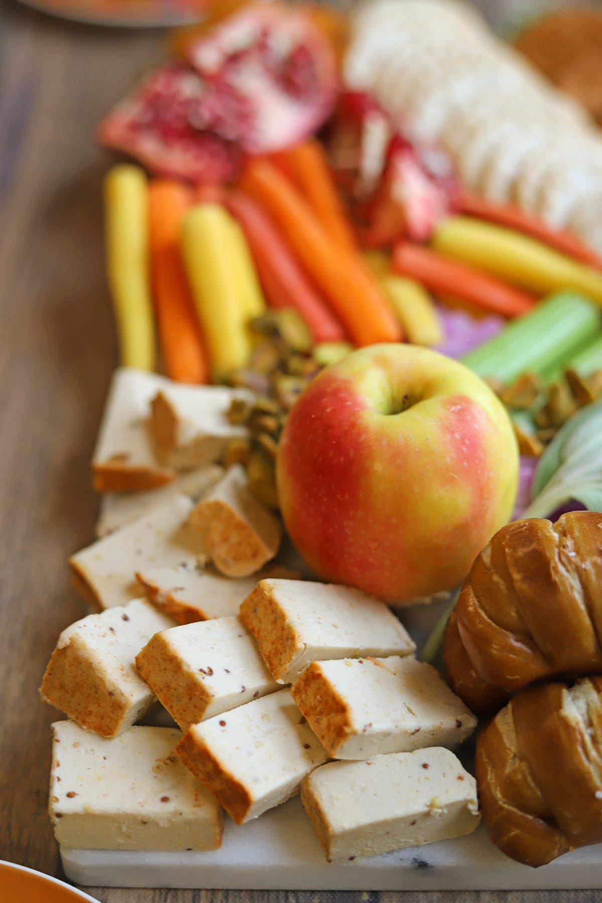 Vegan mustard cheese on Thanksgiving cheese board with apple and veggies.