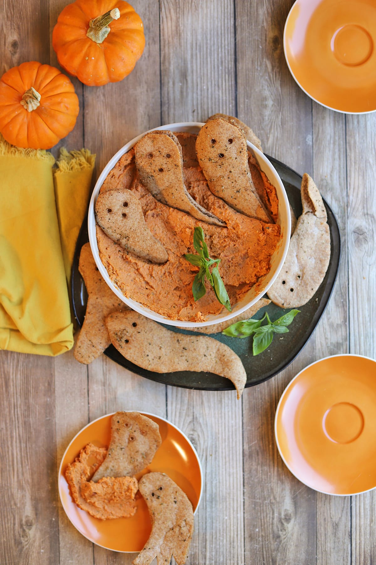 Vegan Halloween snacks on table: crispy pita ghosts and sun-dried tomato hummus.