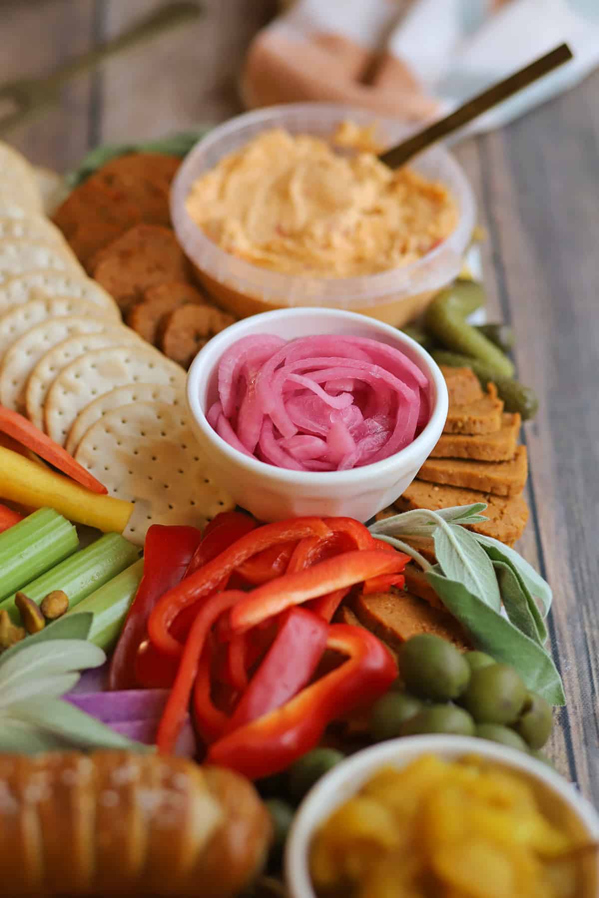 Pickled onions on Thanksgiving charcuterie board with crackers, veggies, olives, vegan pepperoni, and pimento cheese.