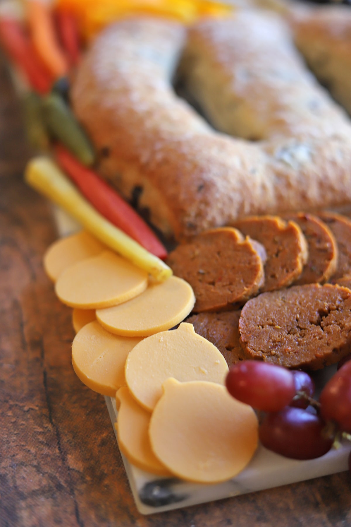 Vegan cheddar pumpkins and seitan pepperoni on Halloween charcuterie board.