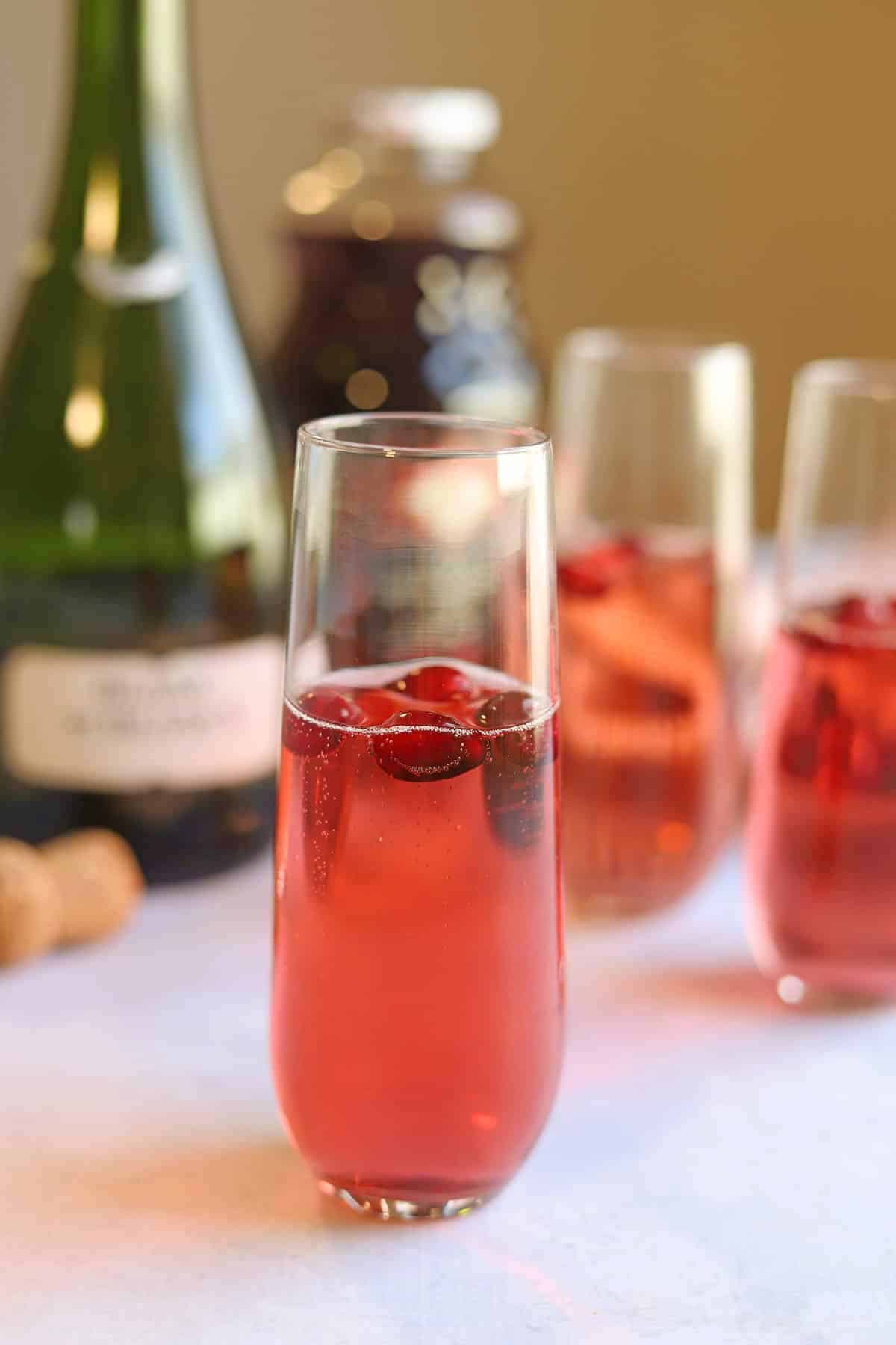 Easy champagne cocktail with fresh cranberries and cranberry juice on table.