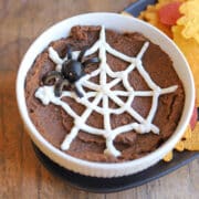 Black olive spider on bowl of chipotle black bean dip with non-dairy sour cream spider web.
