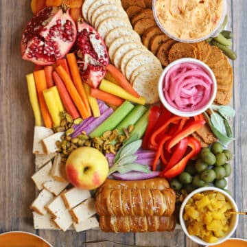 Vegan charcuterie board with vegan pepperoni, apple chutney, pickled onions, and veggies on board.