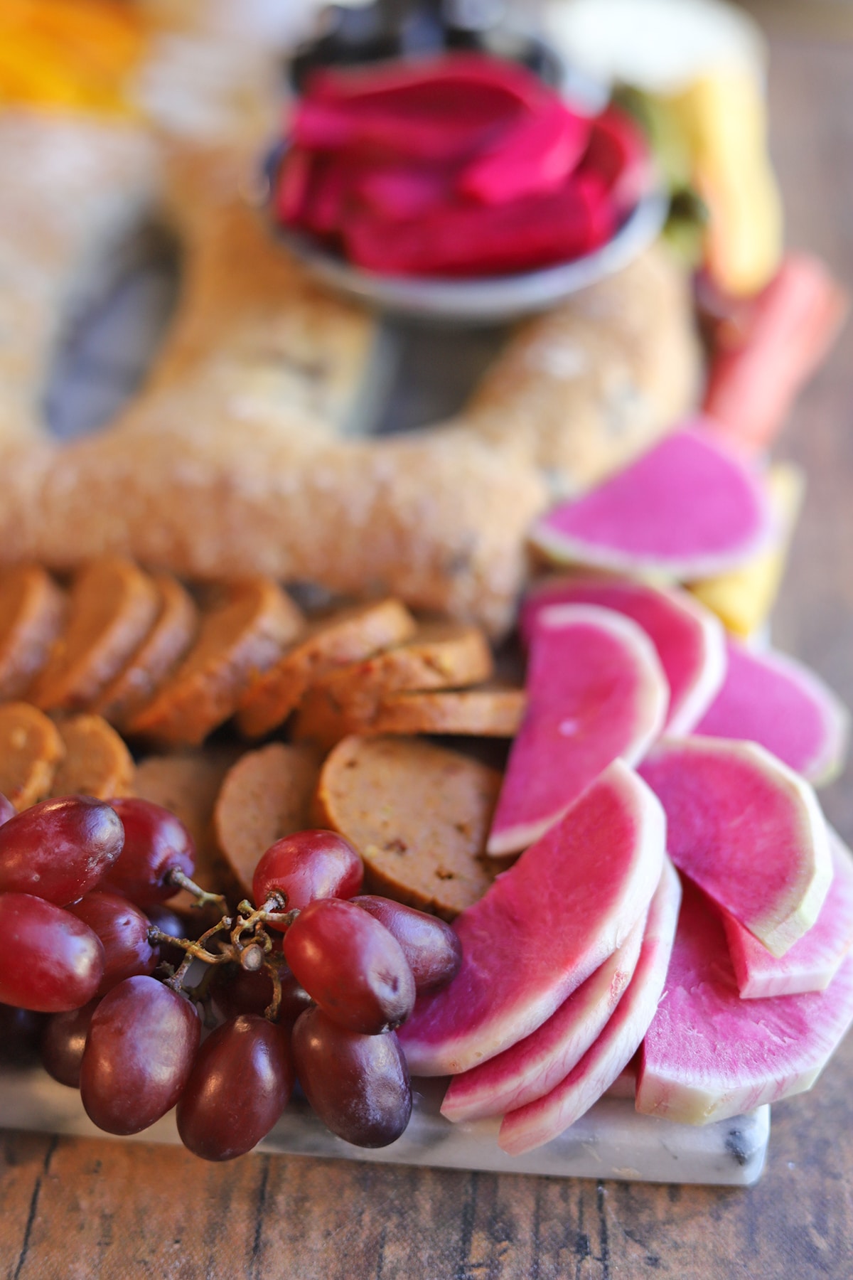 Thinly sliced watermelon radishes, grapes, and pepperoni on Halloween charcuterie board.