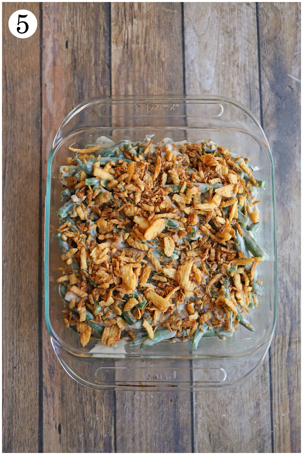 Vegan green bean casserole in dish, topped with fried onions.