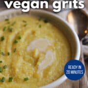 Text overlay: creamy vegan grits, ready in 20 minutes, get the recipe at cadryskitchen.com. Bowl of vegan grits topped with chopped chives.