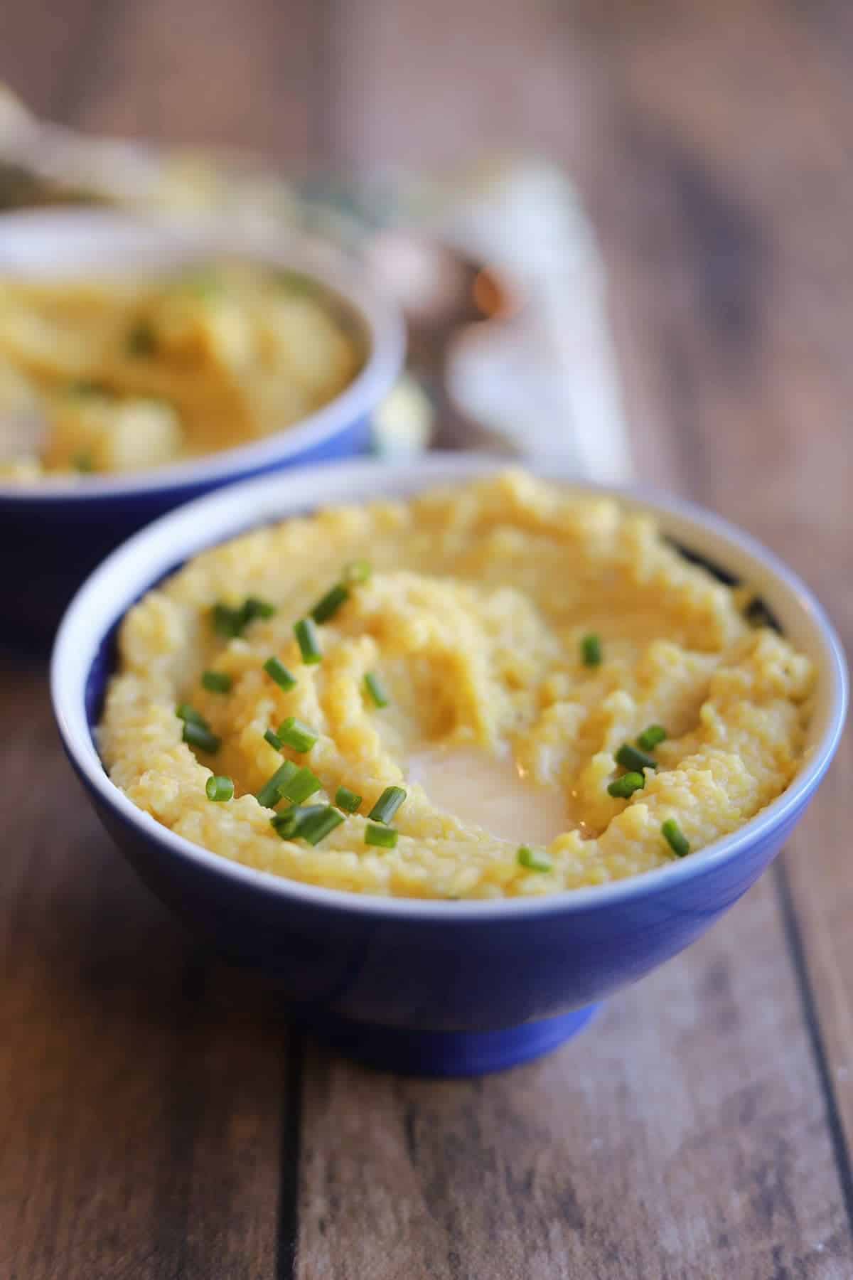 Blue bowls with vegan grits breakfast, topped with chives.